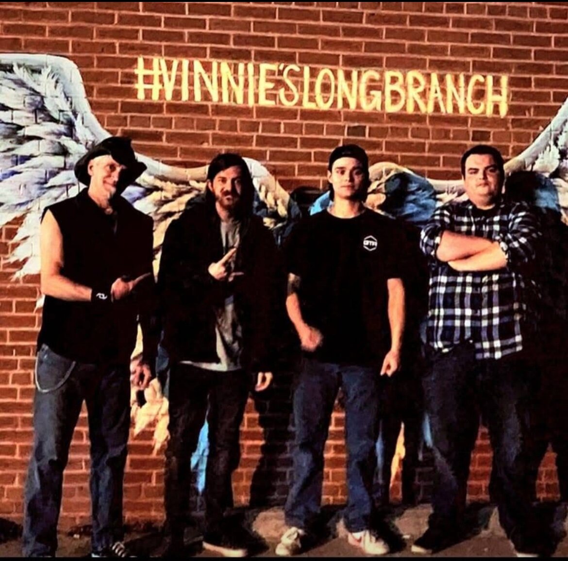 A band posing at the Vinnie's wings mural